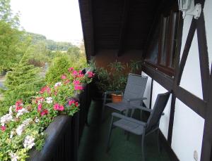 einen Balkon mit zwei Stühlen und Blumen darauf in der Unterkunft Ferienhaus und Privatvermietung Andrea Giesecke in Meiningen