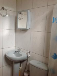 a bathroom with a sink and a toilet and a mirror at Trindade Hospeda - Estúdios Vila C in Trindade