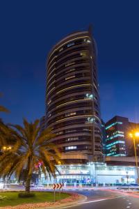 a tall building with a palm tree in front of it at Pearl Executive Hotel Apartments in Dubai