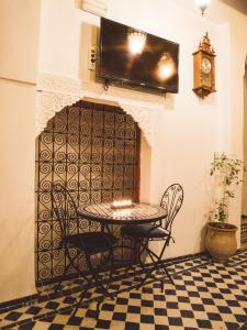 einen Tisch und Stühle in einem Zimmer mit Kamin in der Unterkunft Dar Chrif Idrissi in Fès