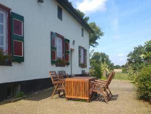 een houten tafel en stoelen buiten een huis bij Ferienhaus Fristerhof in Keeken