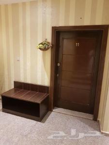 a door with a bench next to a door with a plant at Nadra Furnished Apartments in Taif