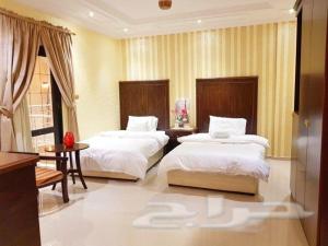 a bedroom with two beds and a table at Nadra Furnished Apartments in Taif