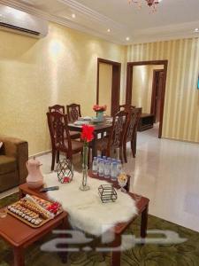 a living room with a table and chairs and a room with at Nadra Furnished Apartments in Taif