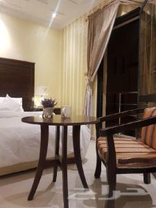 a bedroom with a bed and a table and a bed at Nadra Furnished Apartments in Taif