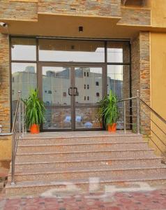 a building with stairs and a glass door with two plants at Nadra Furnished Apartments in Taif