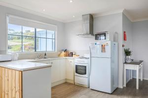 een keuken met een witte koelkast en een wastafel bij Omaroo Cottage Bruny Island in Alonnah