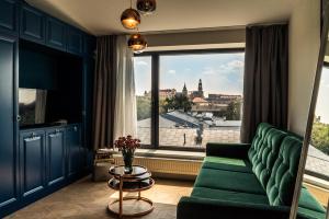 a living room with a green couch and a large window at 3 Minutes Apartments Old Town in Kraków