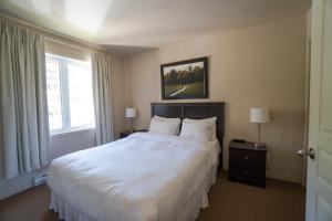 a bedroom with a large white bed and a window at Condos Château-Bromont in Bromont