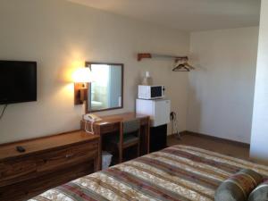 een hotelkamer met een bed, een bureau en een spiegel bij The Monticello Inn in Monticello