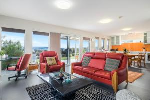 Manfield Seaside Bruny Island في Alonnah: غرفة معيشة مع أريكة حمراء وكراسي