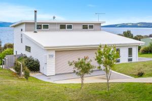 a white house with a garage and a body of water at Manfield Seaside Bruny Island in Alonnah