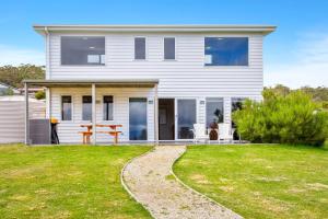 a white house with a table on a lawn at Manfield Seaside Bruny Island in Alonnah