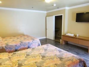 a hotel room with two beds and a flat screen tv at Welcome Inn & Suites Anaheim in Anaheim