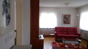 - un salon avec un canapé rouge et une fenêtre dans l'établissement Royal 50, à Loèche-les-Bains