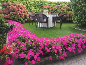 uma mesa com cadeiras e flores cor-de-rosa num jardim em La Casona de Benito em Cudillero