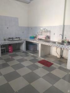 cocina con mesa, fregadero y suelo a cuadros en Rumah Puan Homestay en Bandar Lampung