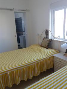 1 dormitorio con 2 camas con rayas amarillas y blancas en Casa Sol, en Carrapateira