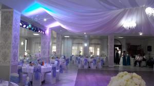 a banquet hall with white tables and chairs and people at Pensiunea Jacqueline in Târgu Jiu