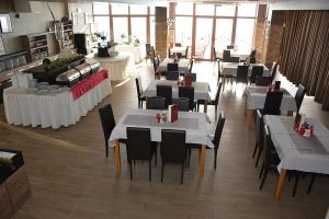 ein Restaurant mit weißen Tischen und Stühlen und Fenstern in der Unterkunft Fabulous Luxury Apartment G7 in Kopaonik