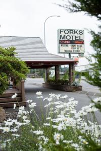 a gas station with a sign and some white flowers at Forks Motel in Forks