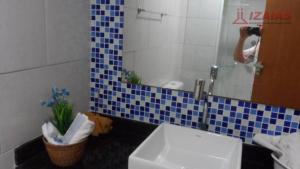 a person taking a picture of a bathroom with a sink at apartamento pra que mais in Ubatuba