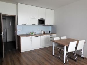 a kitchen with a wooden table and white cabinets at Apartment Potter in Brno