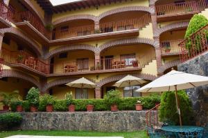 a building with an umbrella and chairs and tables at Posada Rincon Magico in Tepoztlán