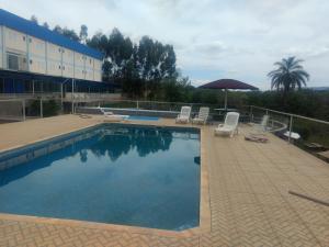 a swimming pool with chairs and an umbrella next to a building at Hotel farol de Minas in Alpinópolis
