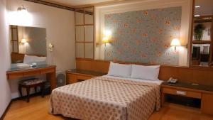 仁愛鄉的住宿－夏都大飯店之分店，卧室配有一张床,墙上挂有绘画作品