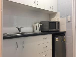 a kitchen with a microwave, sink, and refrigerator at Westside Tavern & Motel in Maryborough