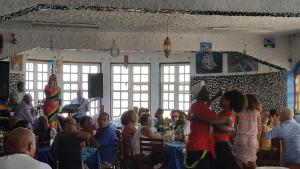 um grupo de pessoas sentadas em mesas em um restaurante em Chez Loutcha Residencial em Mindelo