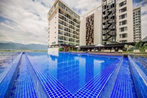 a large swimming pool with two tall buildings at Quinter Central Nha Trang in Nha Trang