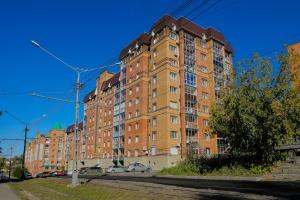 a large brick building with cars parked in front of it at Apart Petrovskie on Sovetskaya 60 in Tomsk