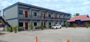a white car parked in a parking lot in front of a building at Langgura Baron Resort in Pantai Cenang