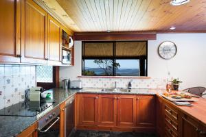 cocina con armarios de madera, fregadero y ventana en Magic Mountain at Smiths Lake, en Smiths Lake