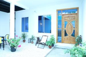 a porch with a wooden door and chairs and plants at Moodhu Surf House in Himmafushi