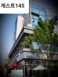 Un edificio alto con un albero davanti di Guest 145 a Gwangju