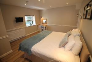 una camera da letto con un grande letto con cuscini bianchi di Number 18 Apartments a Exeter