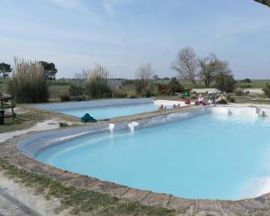 a large pool of blue water with people in it at Tuscania Terme Suites Apartments in Tuscania