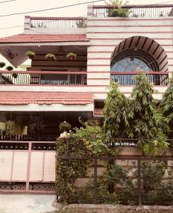 a building with a fence and trees in front of it at Aashray Homestay in Varanasi