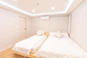 Dawoo House 1 in Hongdae في سول: سريرين في غرفة نوم بجدران بيضاء وأرضية خشبية