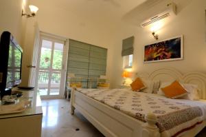 a bedroom with a large white bed and a television at Aashray Homestay in Varanasi