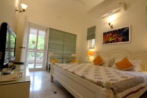 a bedroom with a large white bed and a television at Aashray in Varanasi
