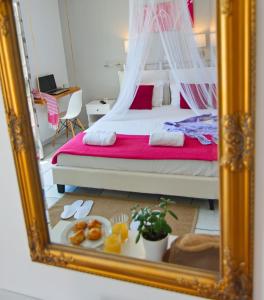 espejo reflejo de un dormitorio con cama con sábanas rojas en Camara Hotel, en Agios Prokopios