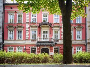 a pink building with a balcony in front of a tree at Elegant Apartments in Krakow