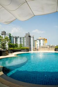 een groot zwembad met gebouwen op de achtergrond bij Golden Pearl Hotel in Bangkok