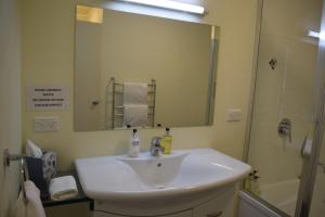 uma casa de banho com um lavatório branco e um espelho. em The Sails em Russell