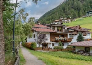 a house in the mountains with a dirt road at Appartement Cristallo in Sölden