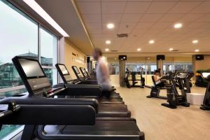 a gym with rows of treadmills and a man on a treadmill at Hotel Villa Glicini in Pinerolo
